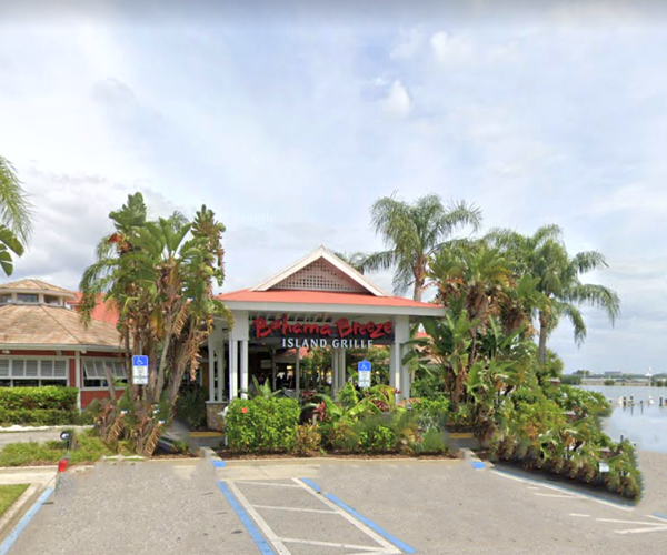 Bahama Breeze Restaurant. View from parking lot at main entrance with palm trees and water in view